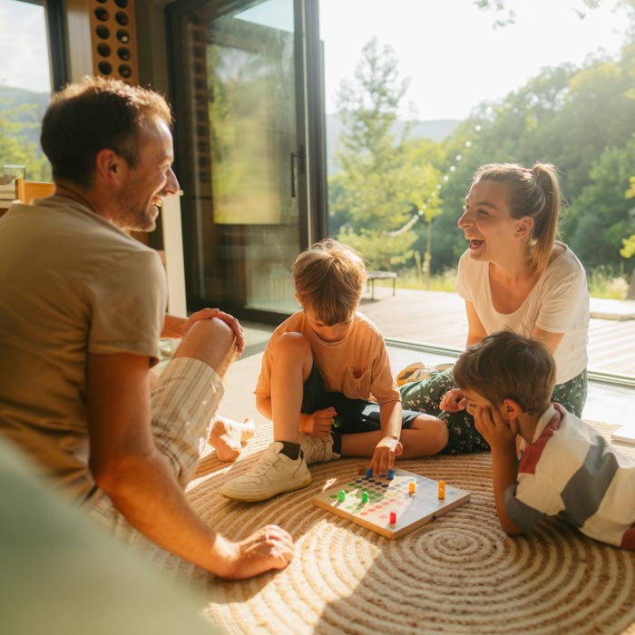 Photo of a young family playing board games together on the floor of their home