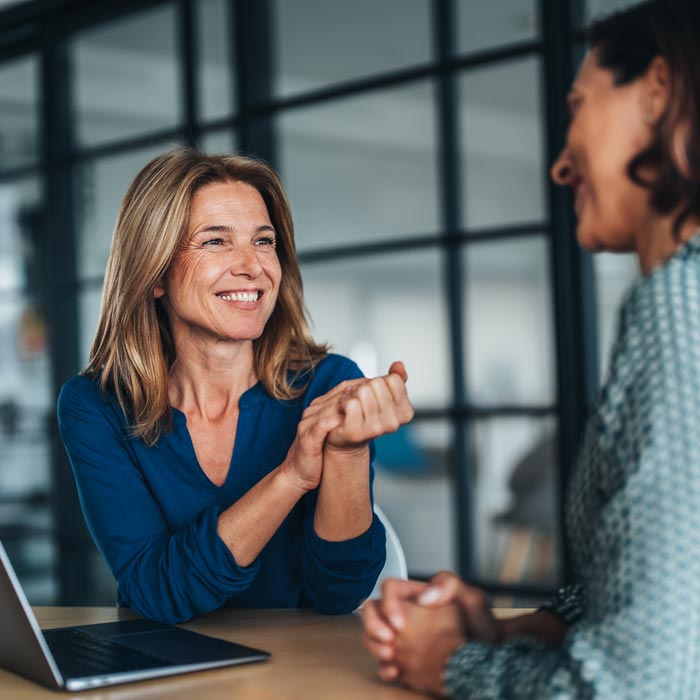 Two women having a focused and friendly conversation at a desk.